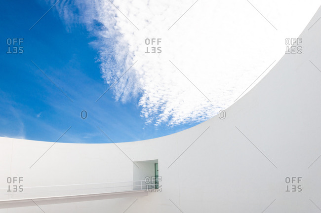 Low angle white minimalist building wall in futuristic style with narrow inclined ramp located under blue sky