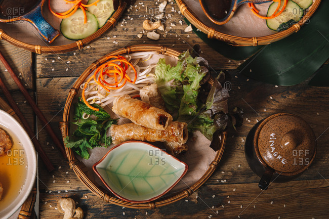 High angle of fried egg rolls served on plate with fresh lettuce and bean sprouts on wooden table in Vietnamese restaurant