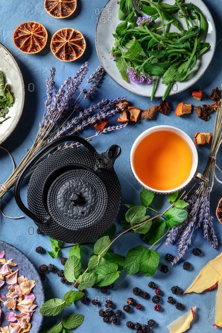 Herbal tea, natural, organic, and healthy. An overhead shot of a cup of tea with a tea pot and an assortment of ingredients, herbs, fruits and flowers