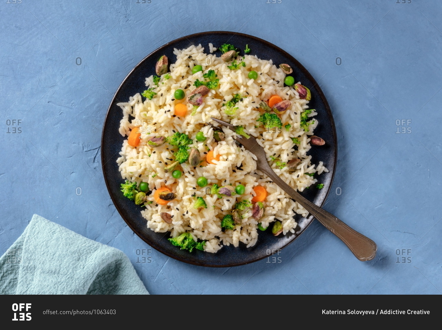 Vegan rice with vegetables, healthy and delicious, the plate is shot from above on a blue background
