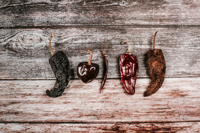 Top view of different dry hot peppers with pedicels and shiny surface on rustic table
