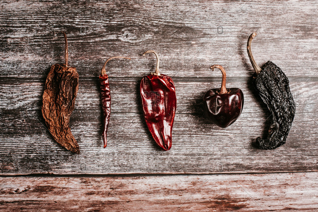 Top view of different dry hot peppers with pedicels and shiny surface on rustic table