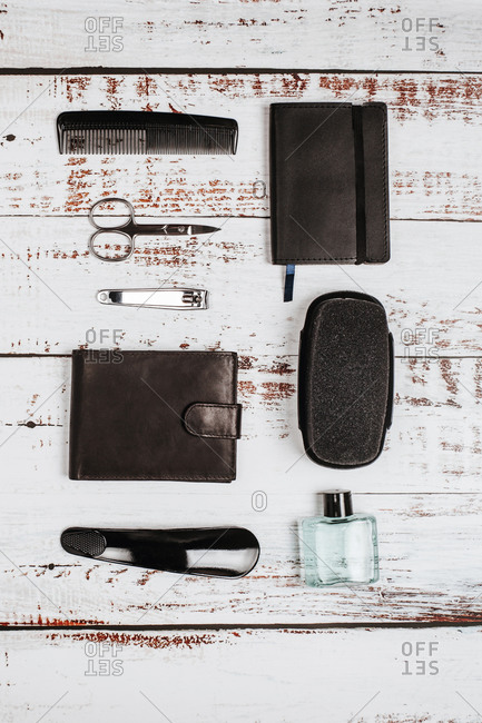 Overhead view of male manicure kit near bottle of perfume and leather purse on shabby surface