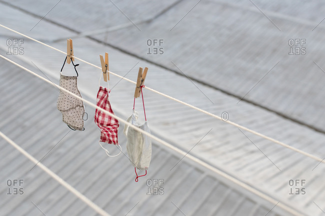 From above of various washed face masks hanging on laundry rope on balcony in city district