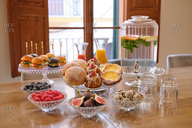 Buffet set with sweet pastry and mini burgers arranged near fresh fruits and berries on table with natural drinks in hotel restaurant