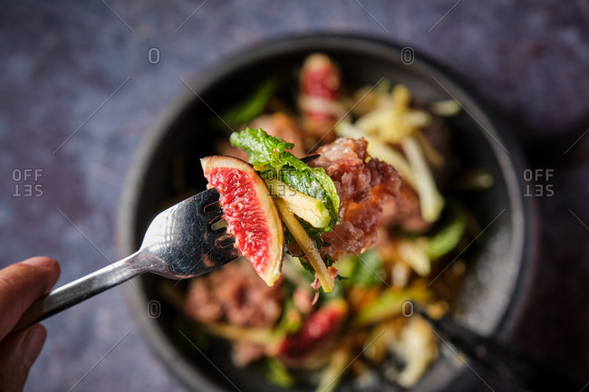 top view of savory pig trotter with fruits and vegetables on fork in luxury restaurant on black background