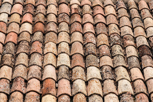 Closeup of weathered rusty red tiles on roof of medieval building for textured background