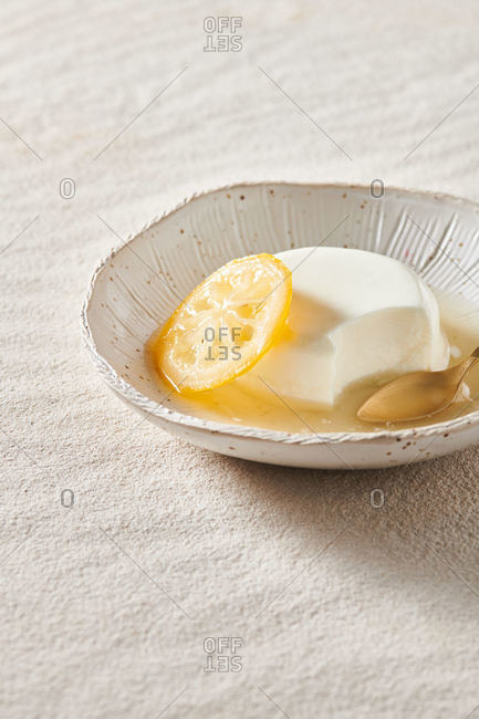 From above of appetizing Italian panna cotta with orange jam in bowl near spoon on table