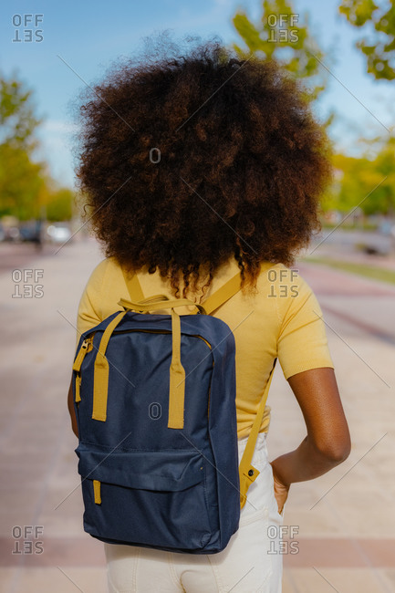 Back view black woman with afro hair with a backpack on her back