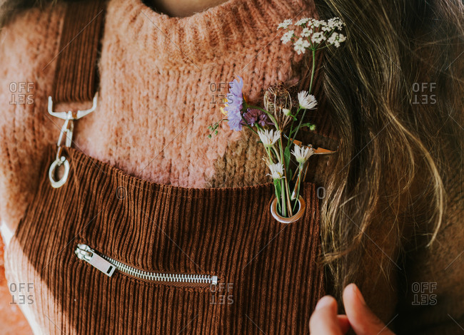 Woman with small flowers in the hold of her brown corduroy overalls