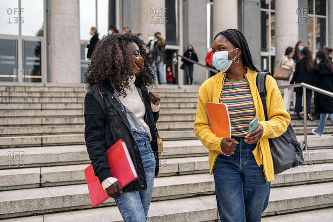 Black students talking after class in college wearing face mask due to covid19 in Madrid, Spain
