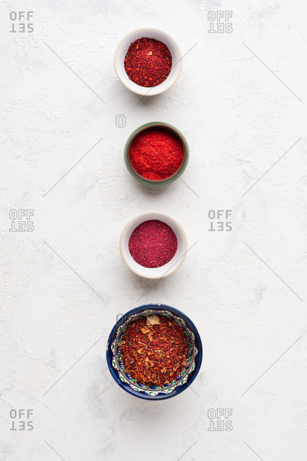 Overhead view of assorted red spices and ingredients over white background
