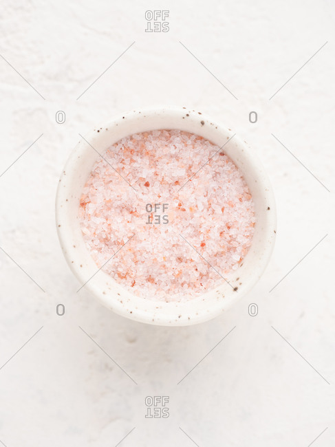 Close-up overhead view of bowl with pink salt over white background