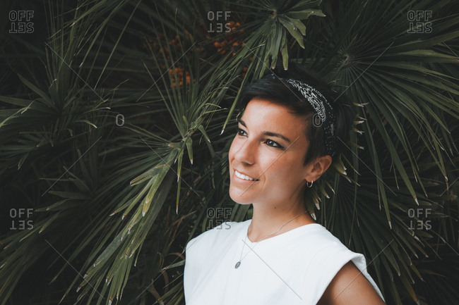 Portrait of a beautiful dreamy woman with a beautiful smile and short hair looking away smiling with plants in the background