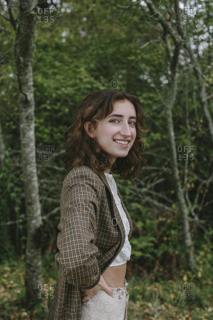 Portrait of happy seventeen year old girl standing in lush forest in Fall, Discovery Park, Seattle, Washington