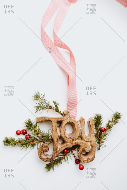 Ribbon and joy sign on white background with pine branches and holly berries