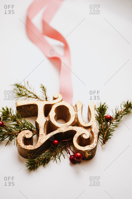 Close up of joy sign with ribbon on white background with pine branches and holly berries