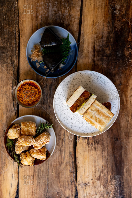 Dishes with Karaage, katsu sando and onigiri served on rustic wooden table