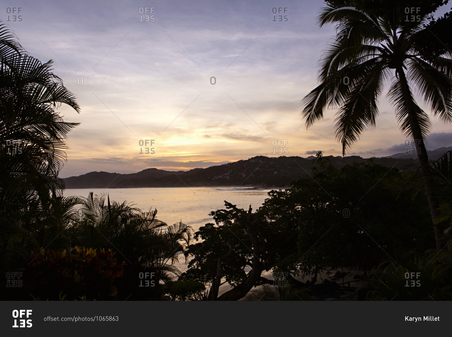 View of a sunset over the Pacific Ocean with palm trees on the coast of Sayulita, Nayarit, Mexico