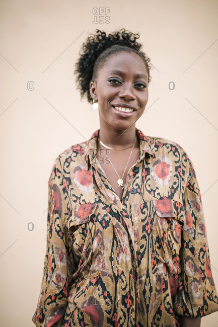 Portrait of young black woman with personality and afro hair on a beige background