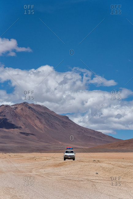 A 4x4 driving through the southwest of the altiplano in Bolivia in a cloudy day
