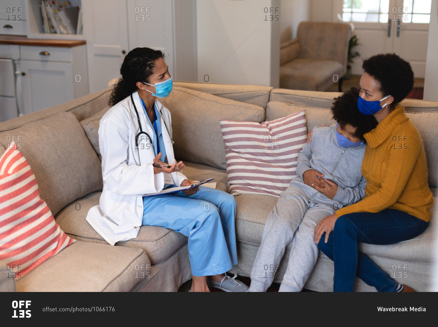 Mixed race mother and daughter talking to mixed race female doctor sitting on couch
