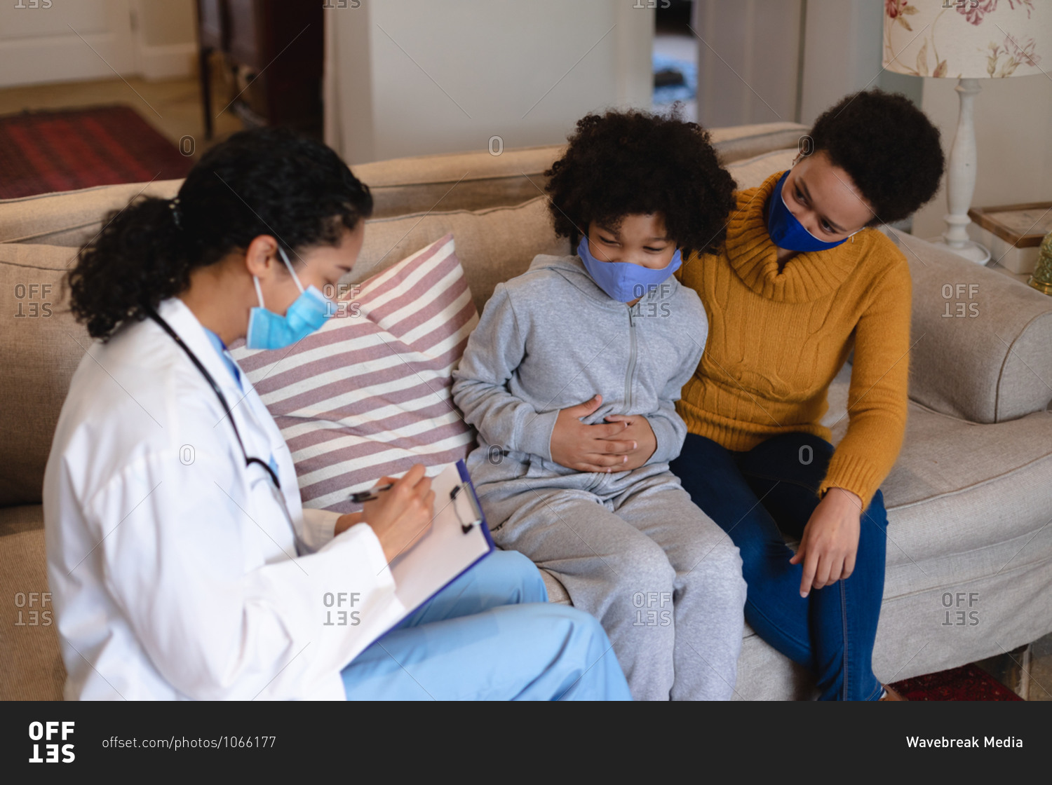 Mixed race mother and daughter talking to mixed race female doctor sitting on couch