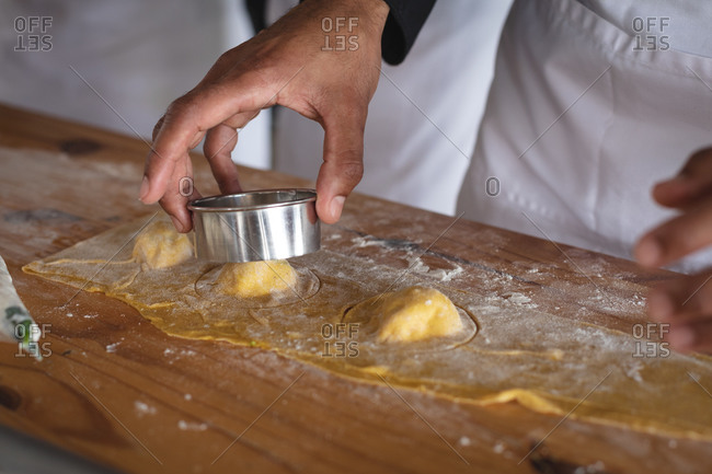 Mid section of chef cutting individual ravioli with stuffing at restaurant kitchen