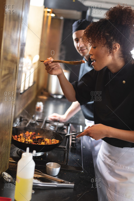 Female african american chef tasting food while cooking at restaurant kitchen