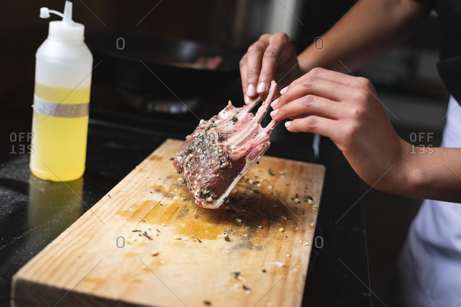 Mid section of chef holding grilled ribs soaked in olive oil on wooden board