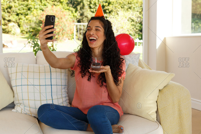 Mixed race woman celebrating birthday having video chat on smartphone