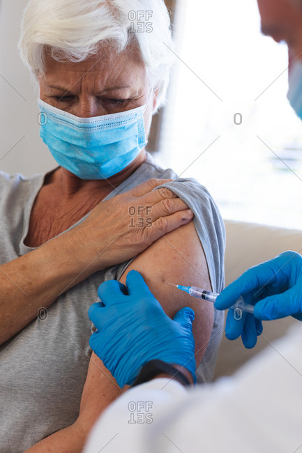 Hands of doctor giving covid19 vaccination to senior caucasian woman