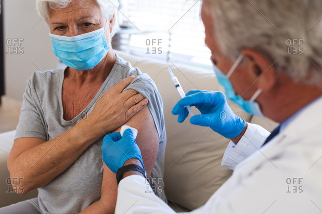 Caucasian male doctor preparing covid19 vaccination for senior woman