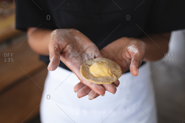 Mid section of chef holding ravioli in hands at restaurant kitchen