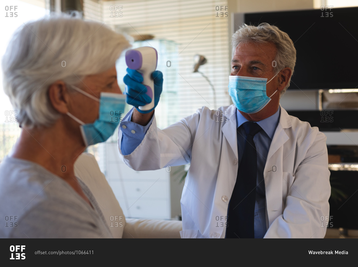 Senior caucasian male doctor taking temperature of senior woman