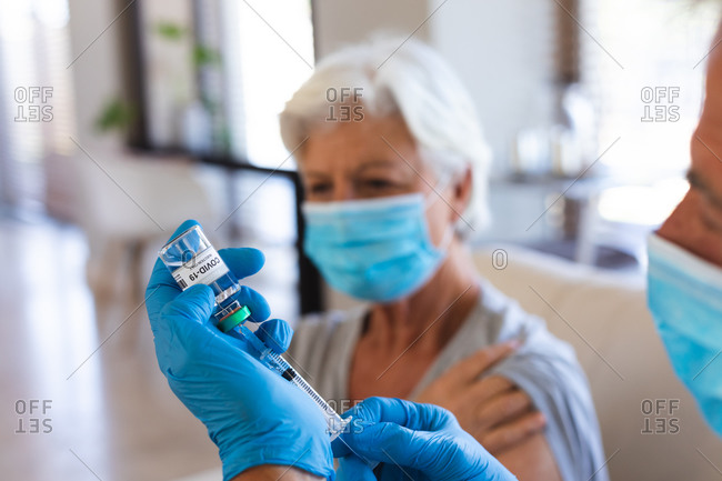 Hands of doctor preparing covid19 vaccination for senior woman