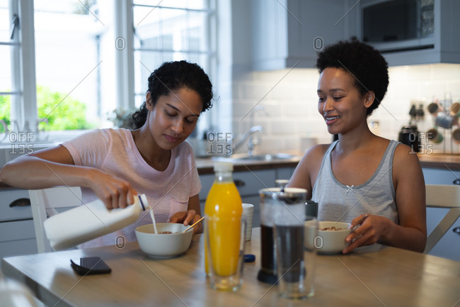 Mixed race same sex female couple having breakfast in kitchen