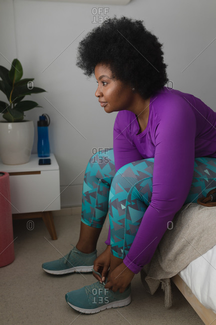 African american woman putting sports clothes on in bedroom