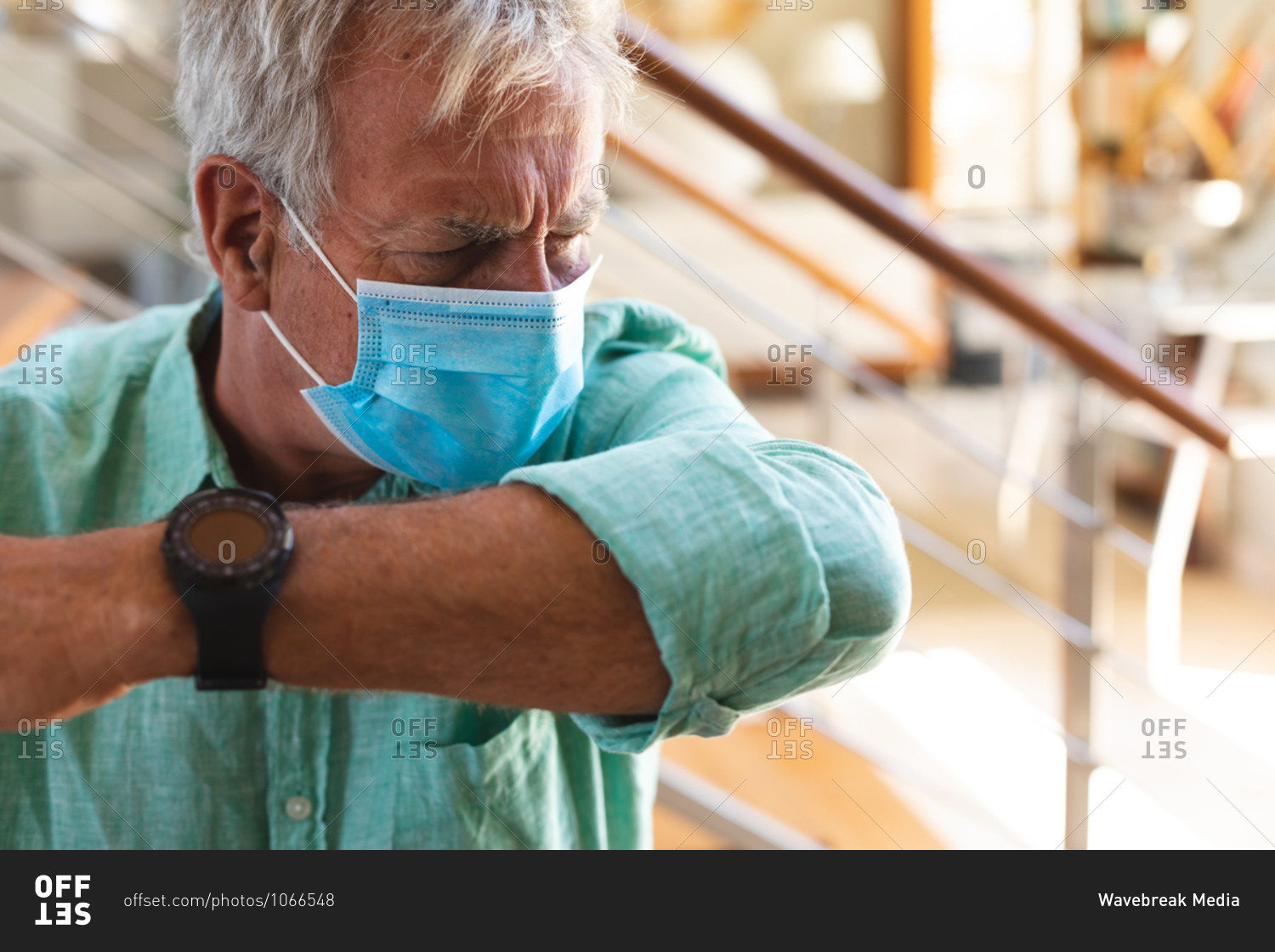 Senior caucasian man wearing face mask coughing into arm