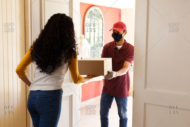 Mixed race woman wearing face mask receiving a package