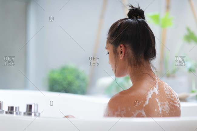 Mixed race woman lying a bathtub at home