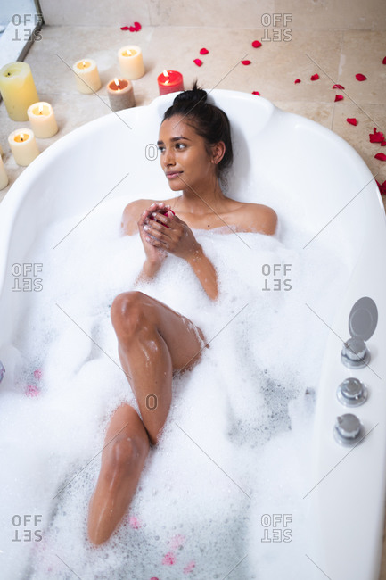 Mixed race woman lying a bathtub at home