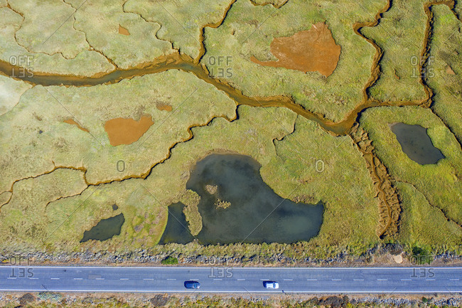 Spain- Andalusia- Aerial view of highway cutting through green marsh in Marismas del Odiel nature reserve