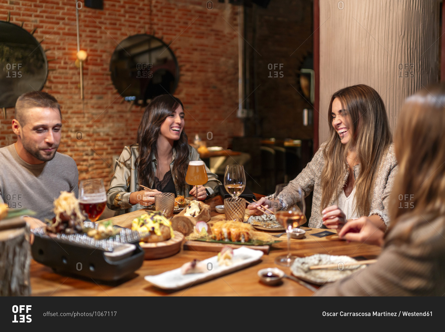 Smiling friends enjoying food and drink while sitting by table at restaurant