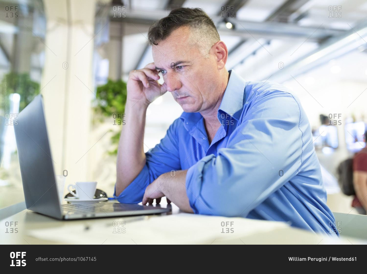 Distressed male professional staring at laptop while sitting in coffee shop
