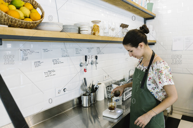 Barista making cold brew coffee while standing in kitchen at coffee shop