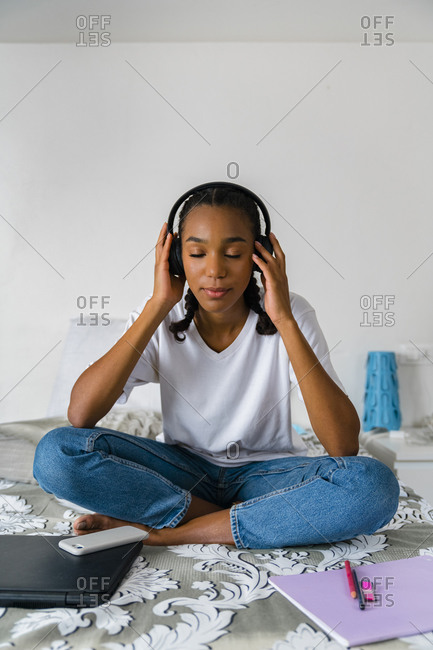 Teenage girl with cross legged listening to music while sitting at home