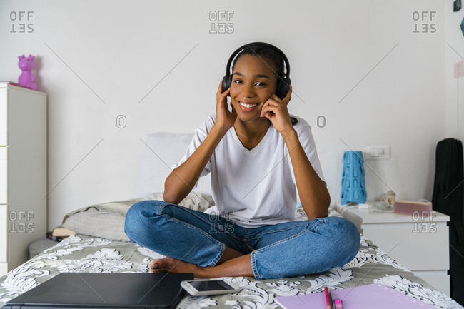 Young girl with cross legged listening to music while sitting at home