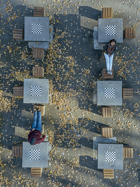 Couple relaxing amidst chess tables in public park during autumn