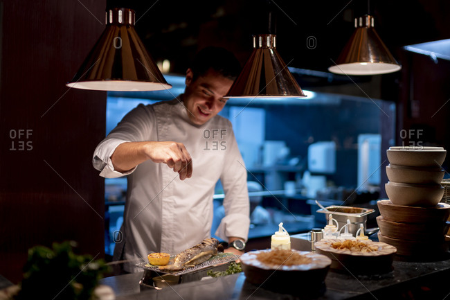Male chef sprinkling seasoning seafood in kitchen at restaurant